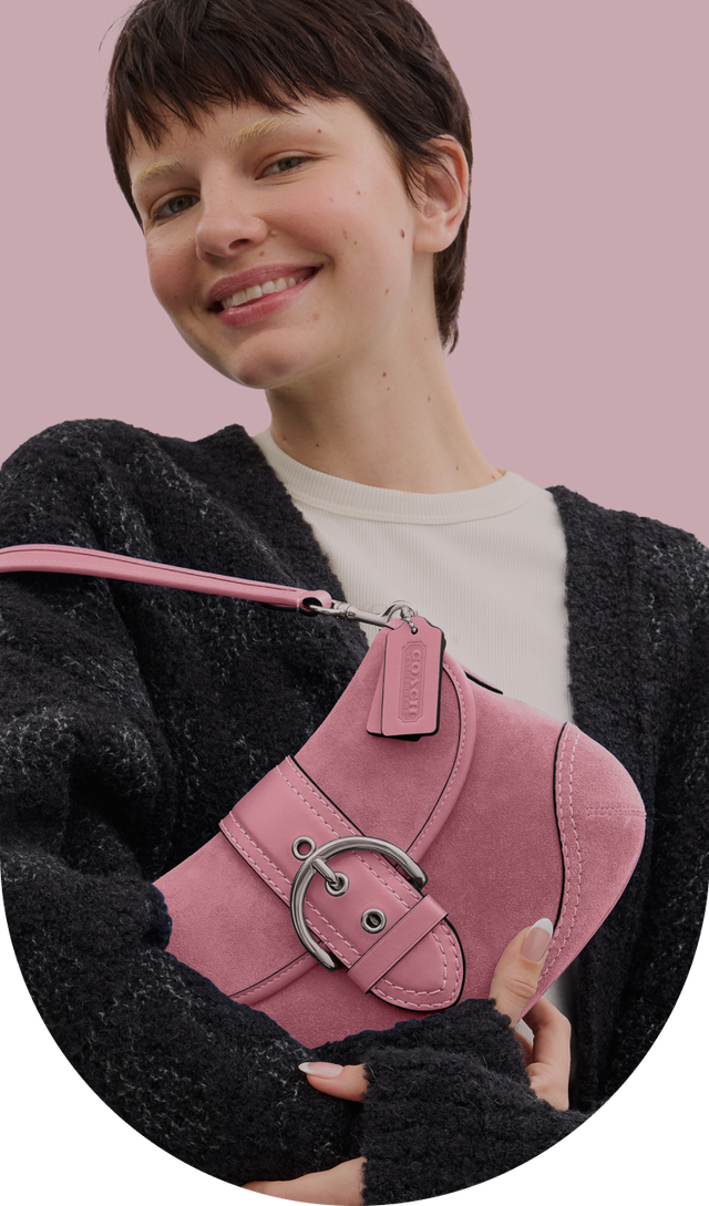 a woman holding a pink purse in her hand