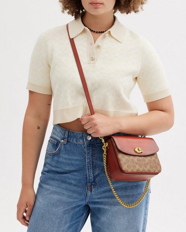 a woman in a white shirt and jeans holding a brown purse