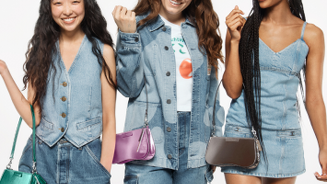 three women in denim outfits holding purses together with smiles