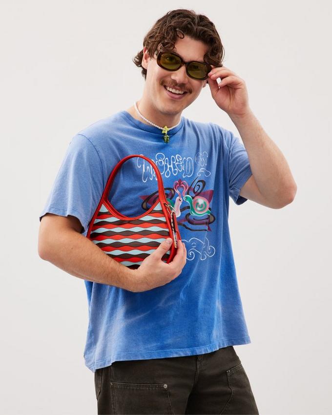 a man in sunglasses holding a purse and talking on the phone