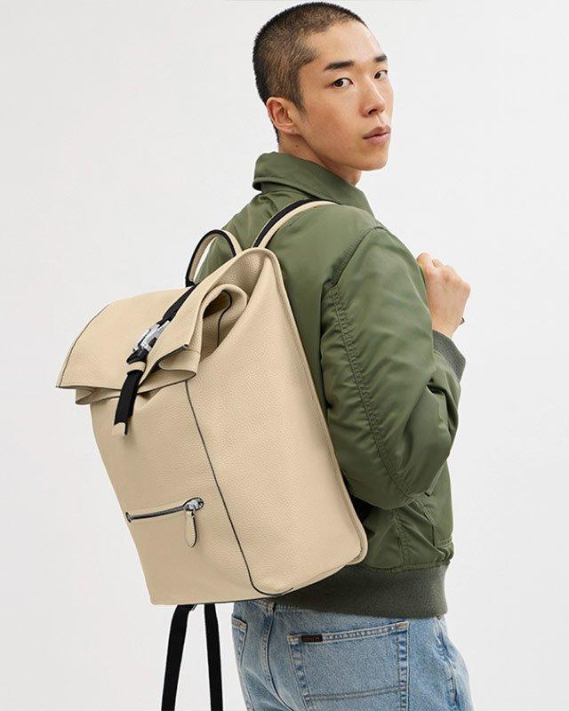 a man in a green jacket and a tan backpack