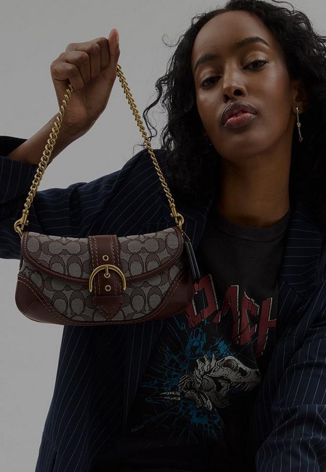 a woman holding a purse with a chain attached to it