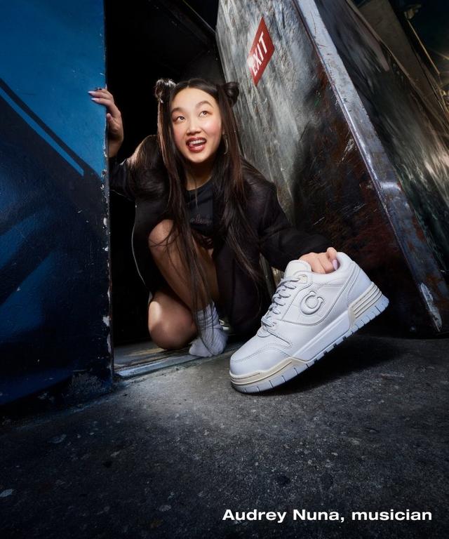 a woman in a doorway with a white sneaker in her hand