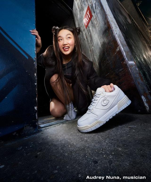 a woman in a doorway with a white sneaker in her hand