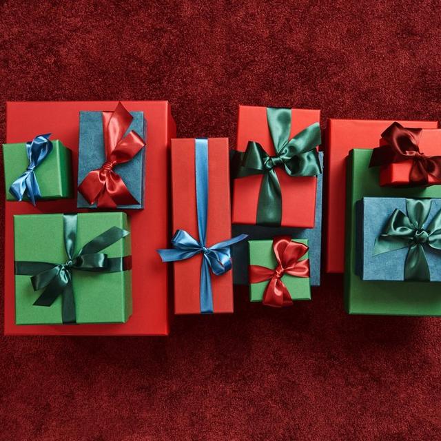 Assortment of wrapped gift boxes in red, green, and blue with coordinating satin ribbon bows.