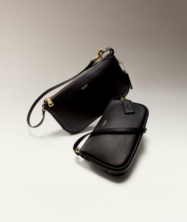 Two black Coach leather crossbody bags with gold hardware and wrist straps.