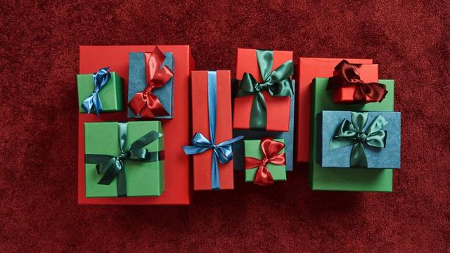 Collection of wrapped gift boxes in red, green, and blue with coordinating satin ribbon bows.