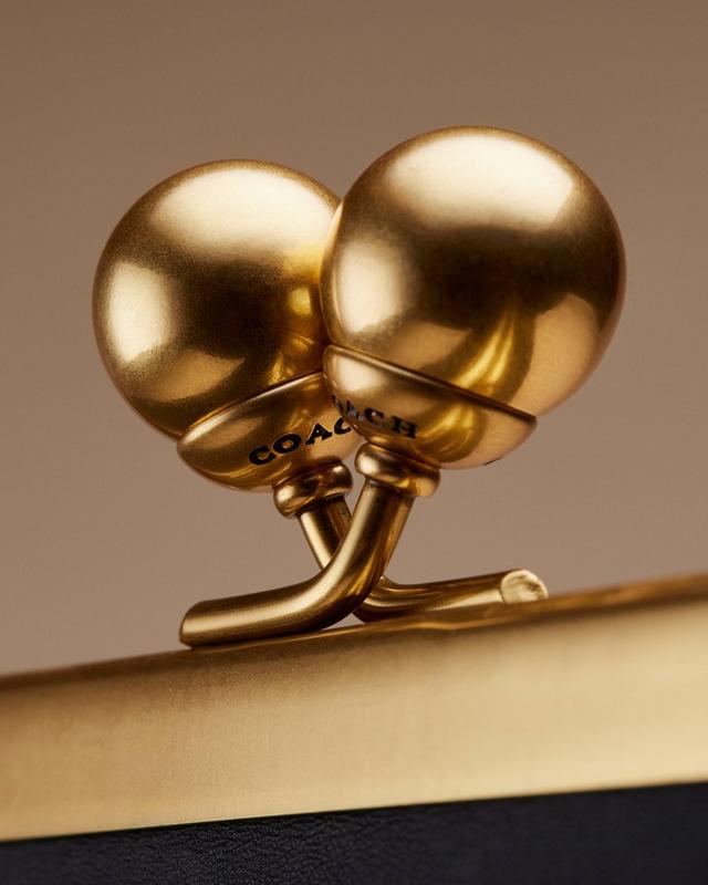 Coach gold-toned clip-on earrings with dome design and brand name engraved on hardware.
