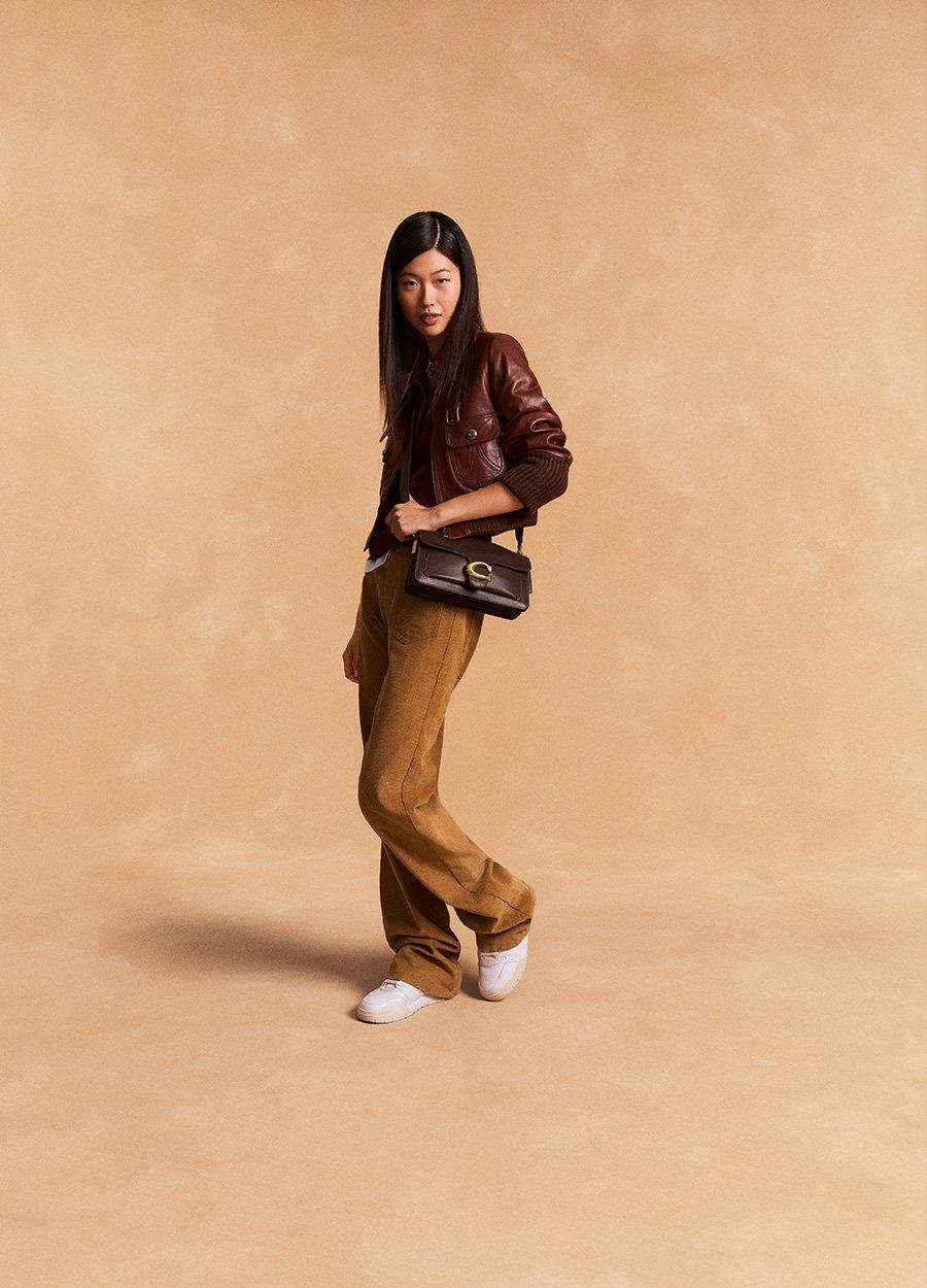 Model standing with shoulder bag