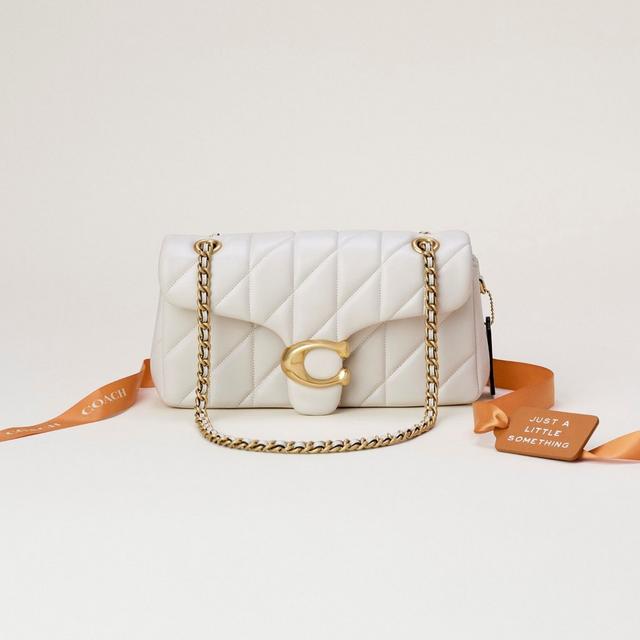 White quilted Coach shoulder bag with gold chain strap and signature C clasp closure.