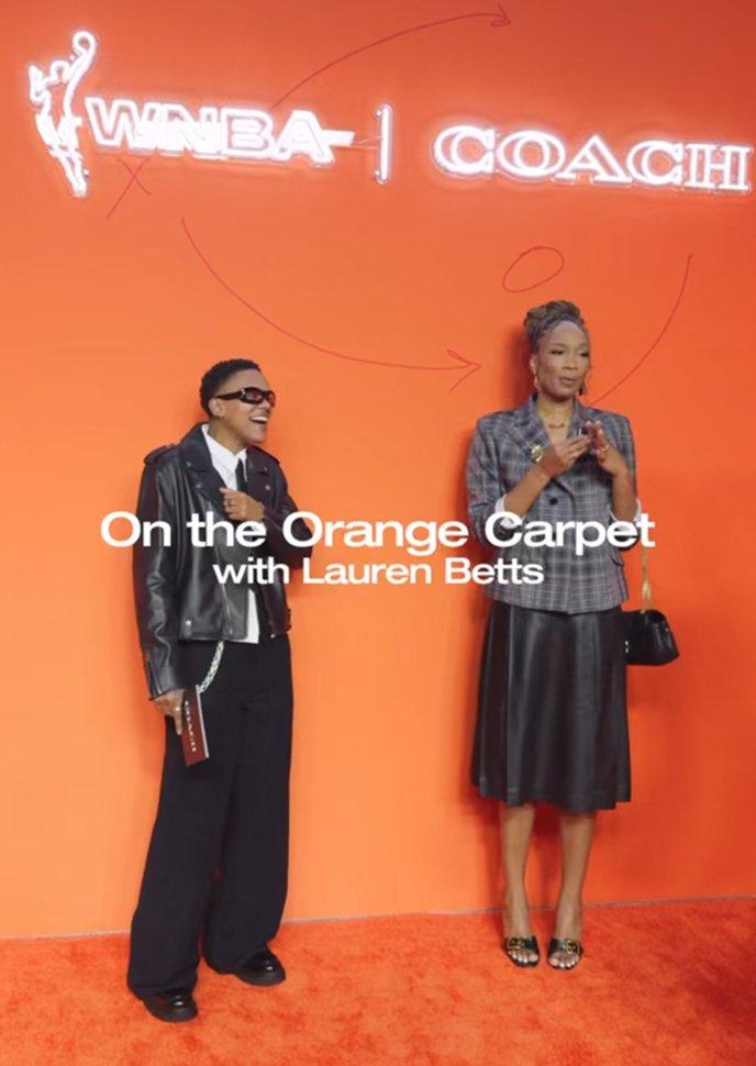 Two people posing on orange carpet.