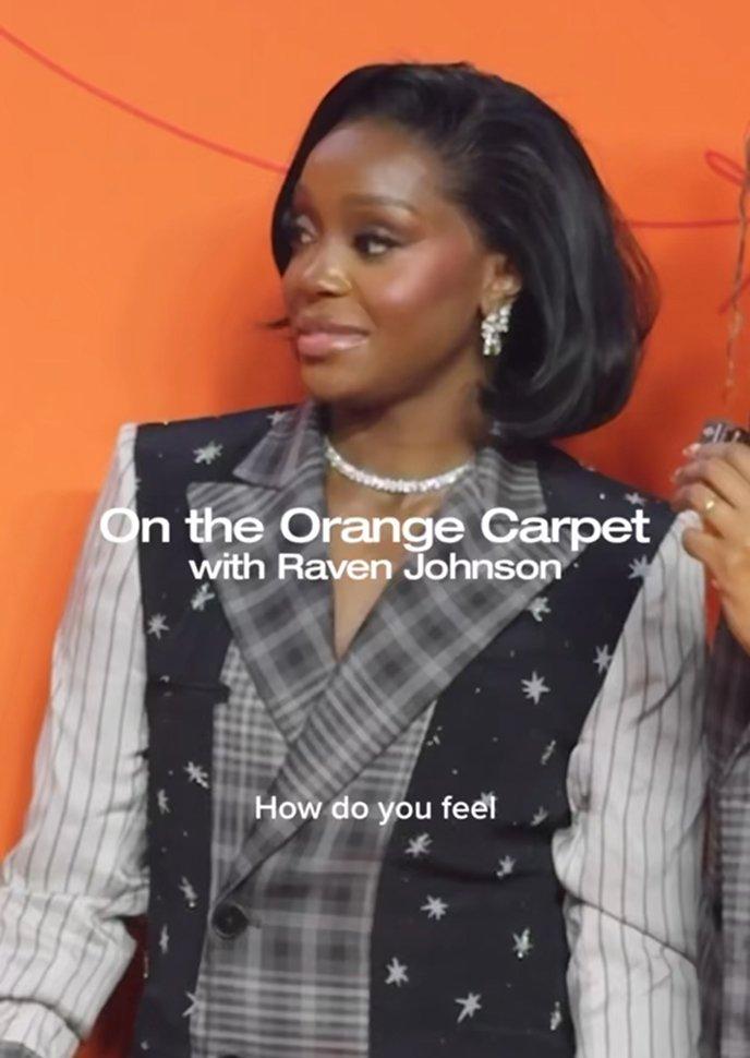 Woman wearing a plaid suit with star-embellished vest and pearl necklace during an interview.