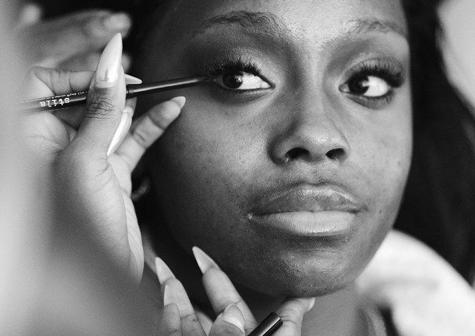 Woman applying mascara to her eyelashes with a makeup brush.
