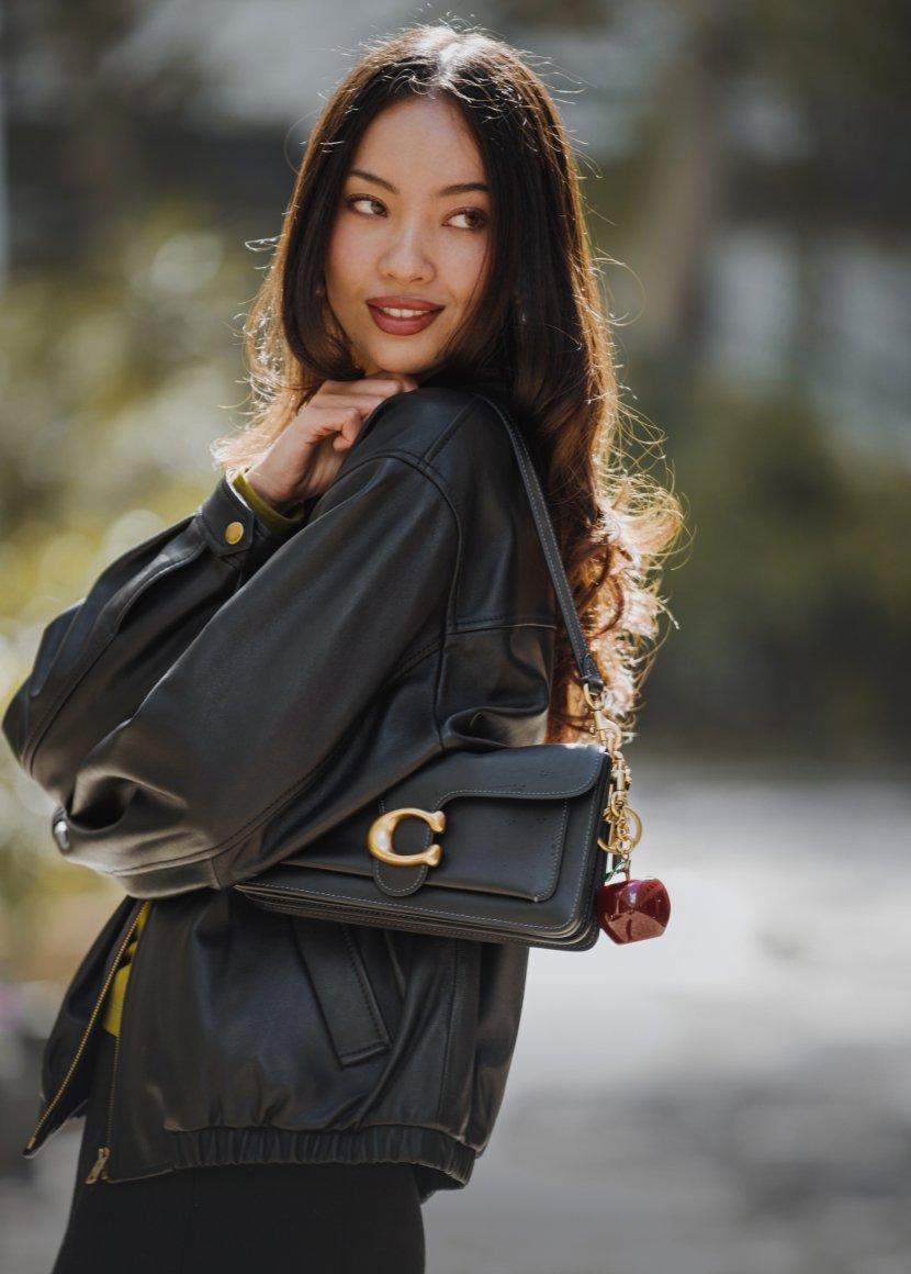 a woman in a black jacket holding a black purse
