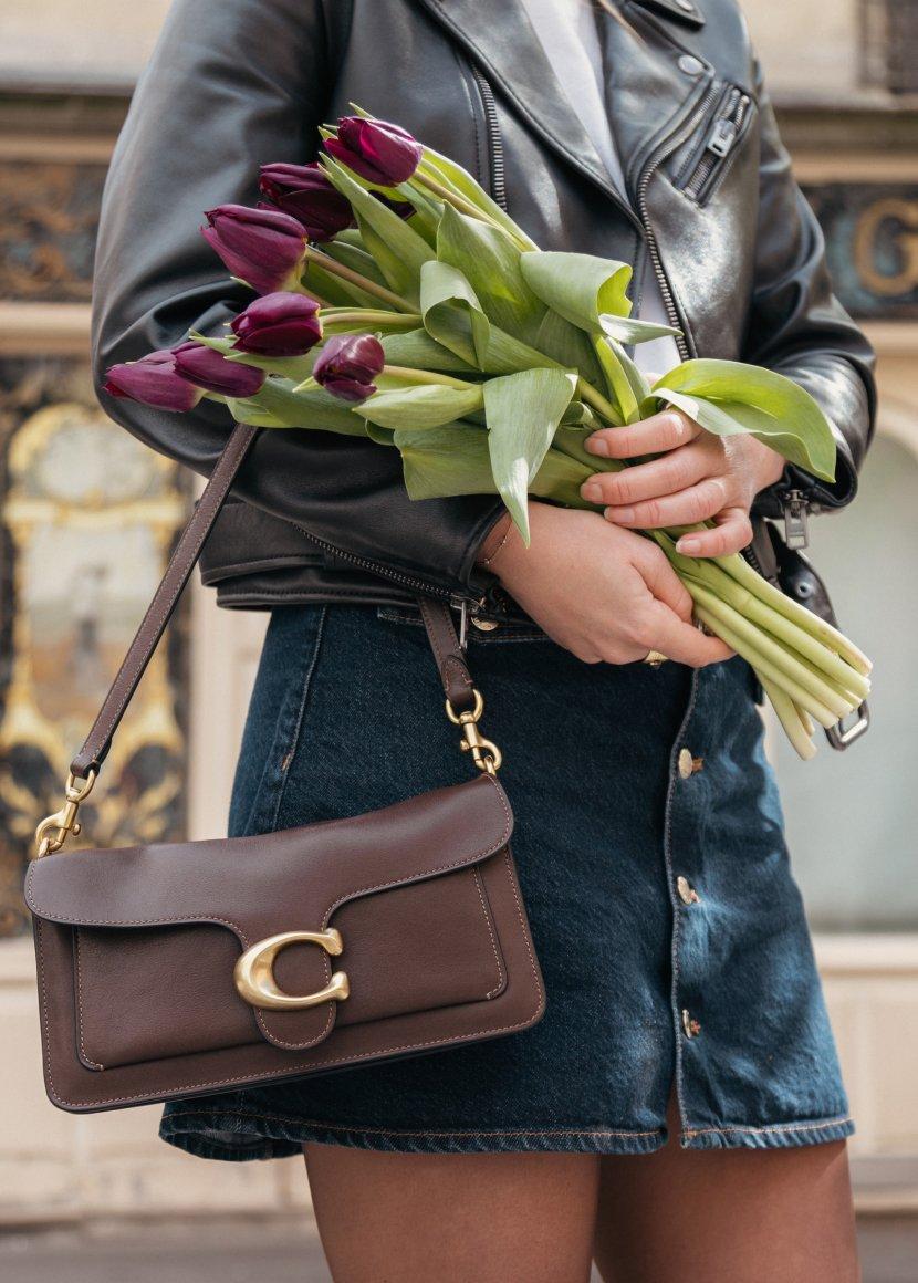 a woman holding a purse and a bouquet of flowers