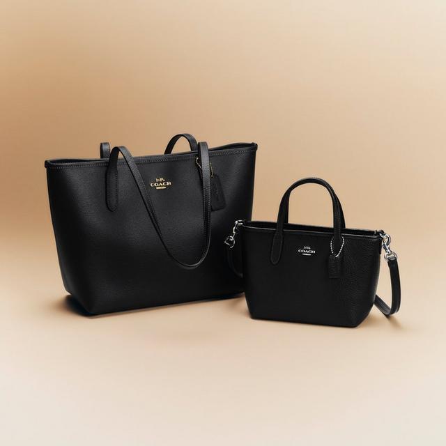 Two black leather Coach tote bags, one large with shoulder straps and one small with handles and crossbody strap.