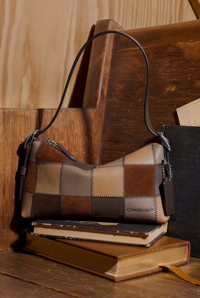 a woman reading a book in a library with a coachtopia scrappy alter ego shoulder bag