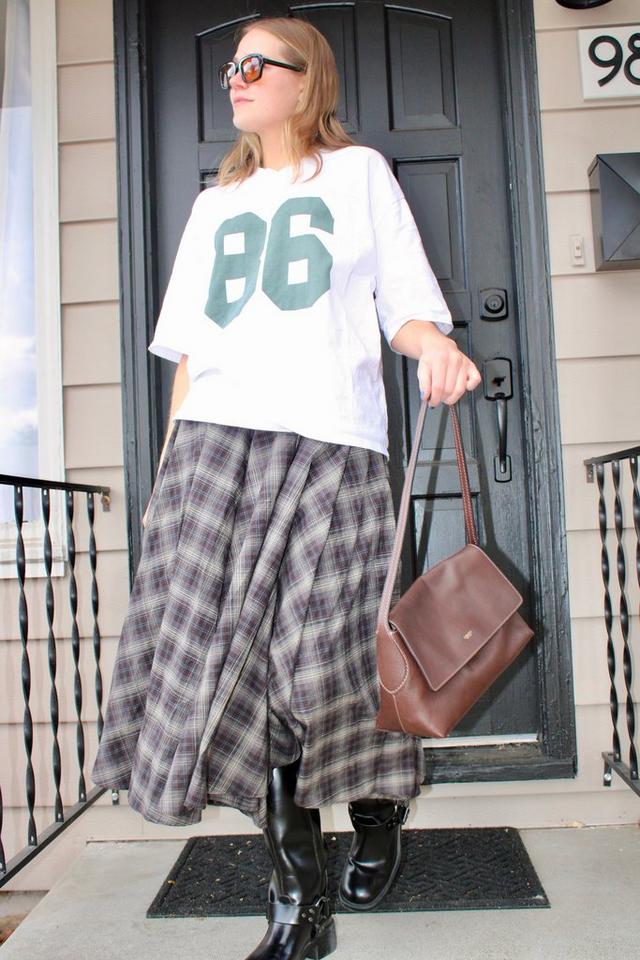 Young woman posing in front of a house wearing a Coach leather Chelsea bag