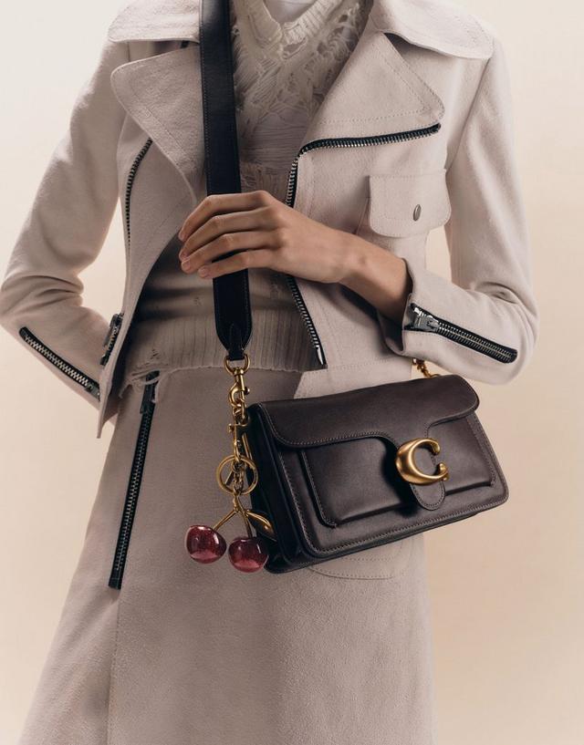 woman carrying Coach Tabby Shoulder Bag in black leather with cherry bag charm