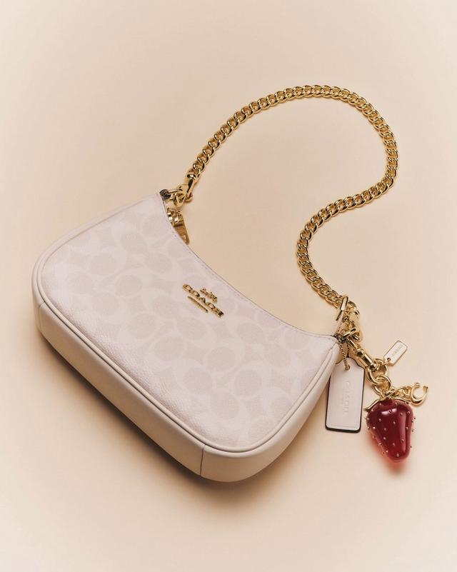 Signature-print Coach handbag with a chain-link strap and strawberry charm