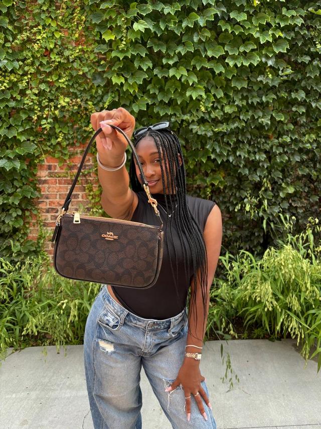 woman holding Coach Nolita 19 in maple Signature Canvas