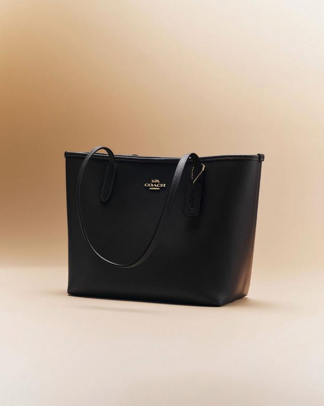 Black leather Coach tote bag with shoulder straps and gold-tone logo hardware.