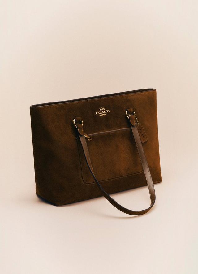 Brown Coach suede tote bag with gold hardware and front pocket.