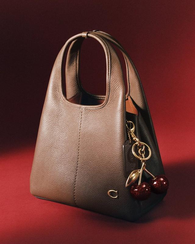 Colorblock leather hobo bag with gold cherry charm keychain attached to handle.