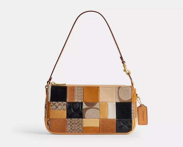 Person wearing oversized glasses and striped shirt holding a patchwork handbag with chain strap.