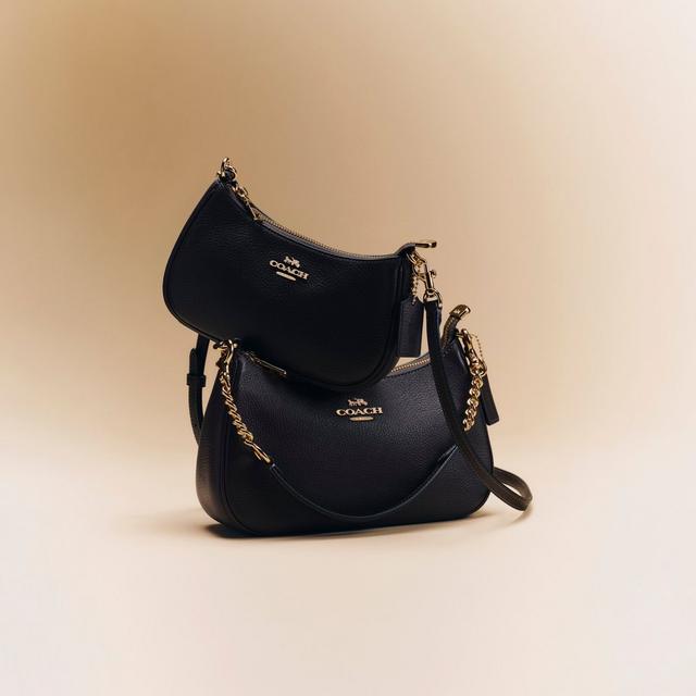Two black leather Coach handbags stacked together with gold chain straps and logo hardware.