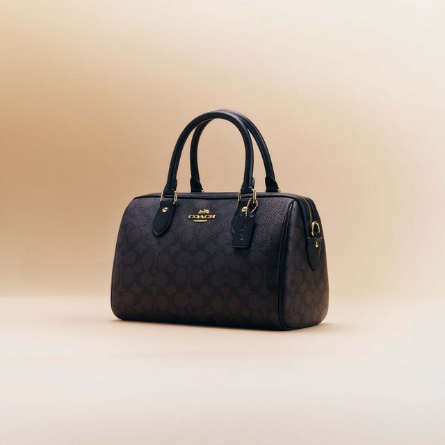 Coach black signature patterned satchel handbag with double handles and gold-tone hardware.