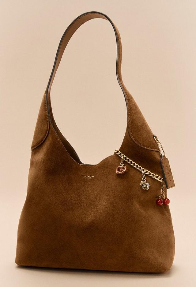 Sac hobo en daim marron Coach avec chaîne dorée et breloques décoratives cerise, cœur et fleur.