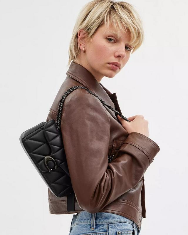 a woman in a brown jacket holding a black bag