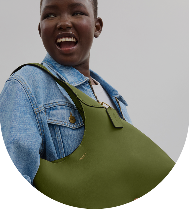 a young woman holding a green purse in her hands