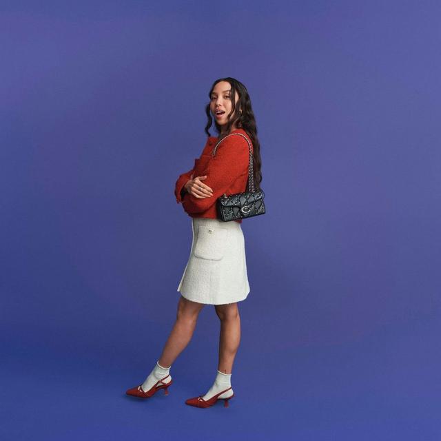 two women in different outfits pose for a photo on a blue background