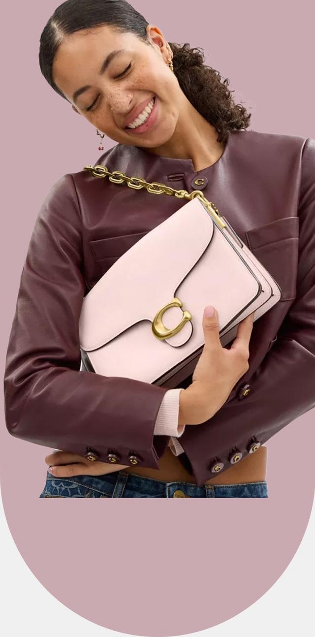 a woman holding a pink purse in her arms while smiling