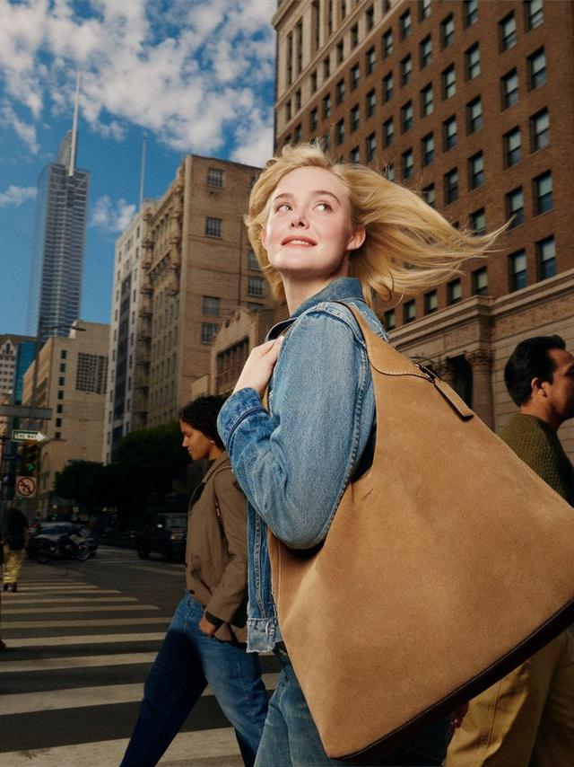 a woman walking down a city street with a large bag