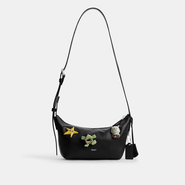 Black leather shoulder bag with gold hardware, featuring playful character charms including a star and hippo.