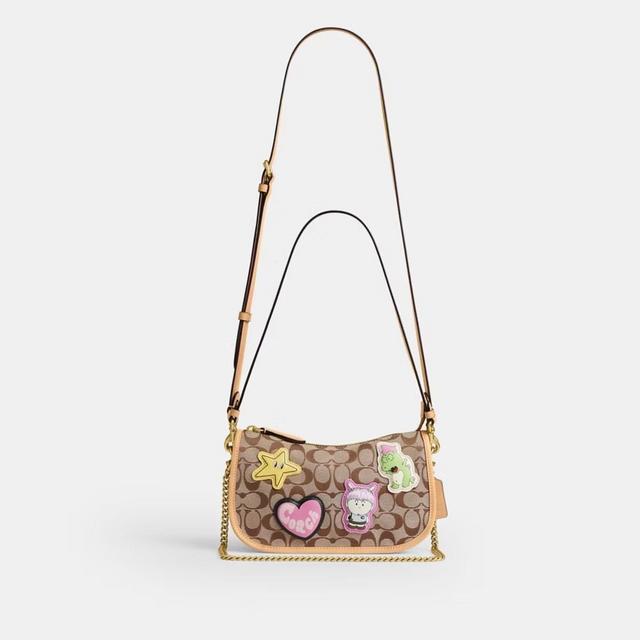 Coach signature crossbody bag with playful patches including star, heart, and character appliques.