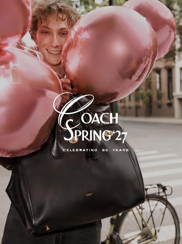 Person wearing pink jacket carrying black Coach leather handbag with gold hardware.