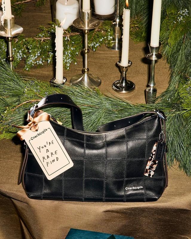 a woman in a skirt and boots holding a green bag