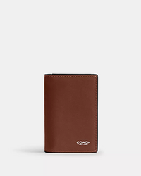 Brown leather bifold wallet with Coach logo in silver at bottom right corner.