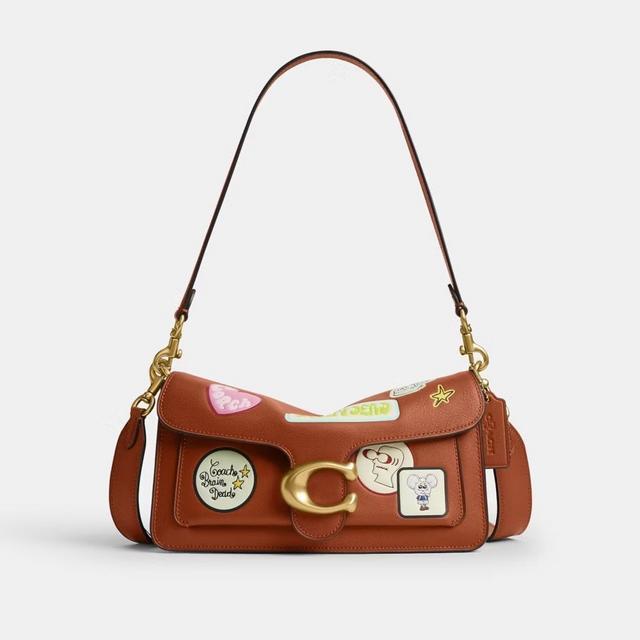 A brown leather shoulder bag with gold hardware. It features patches of the Coach | Brain Dead mascot and motifs.