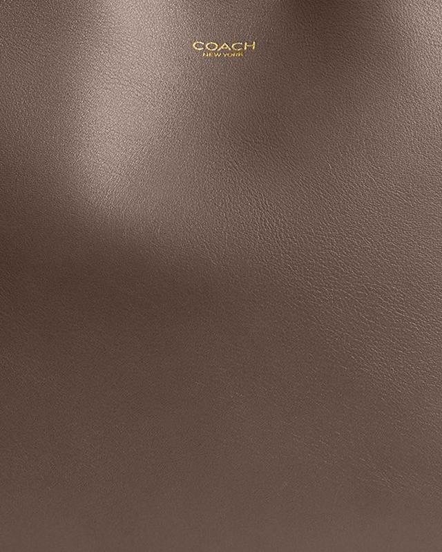COACH New York logo embossed on brown leather surface.
