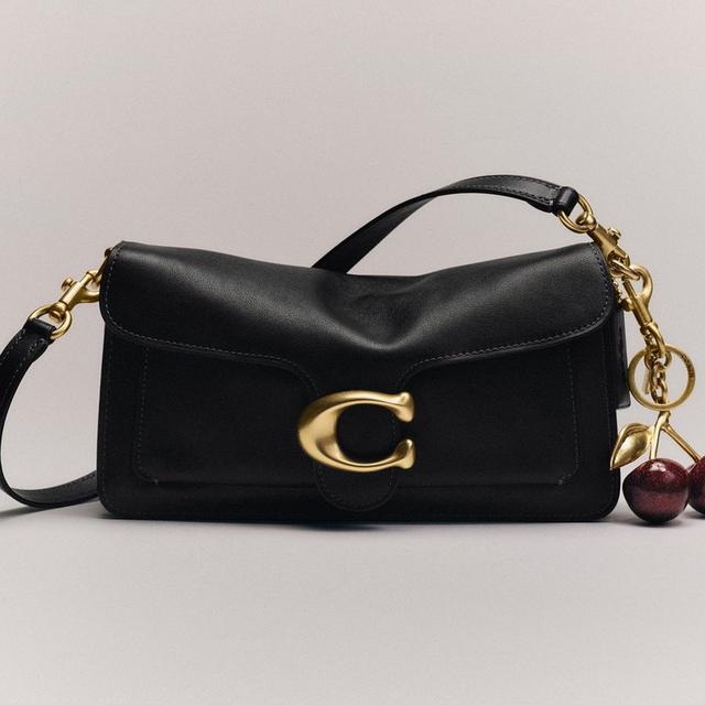 Black leather shoulder bag with gold C logo clasp and decorative cherry charm attached.