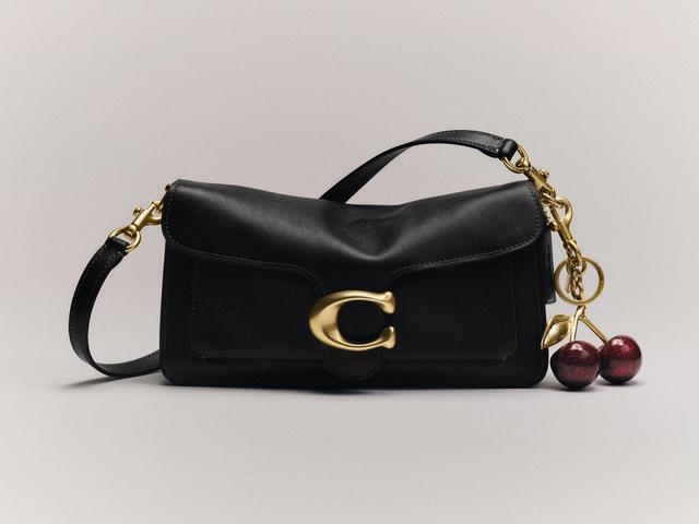Black leather shoulder bag with gold C logo clasp and decorative cherry charm attached.